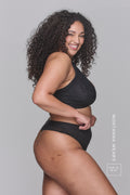 A woman modelling a black lace and mesh bra paired with matching knickers
