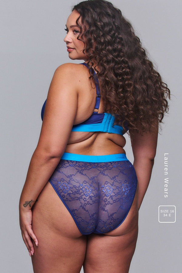 A woman standing with her back turned modelling a Navy Lace Brief paired with a matching bralette 