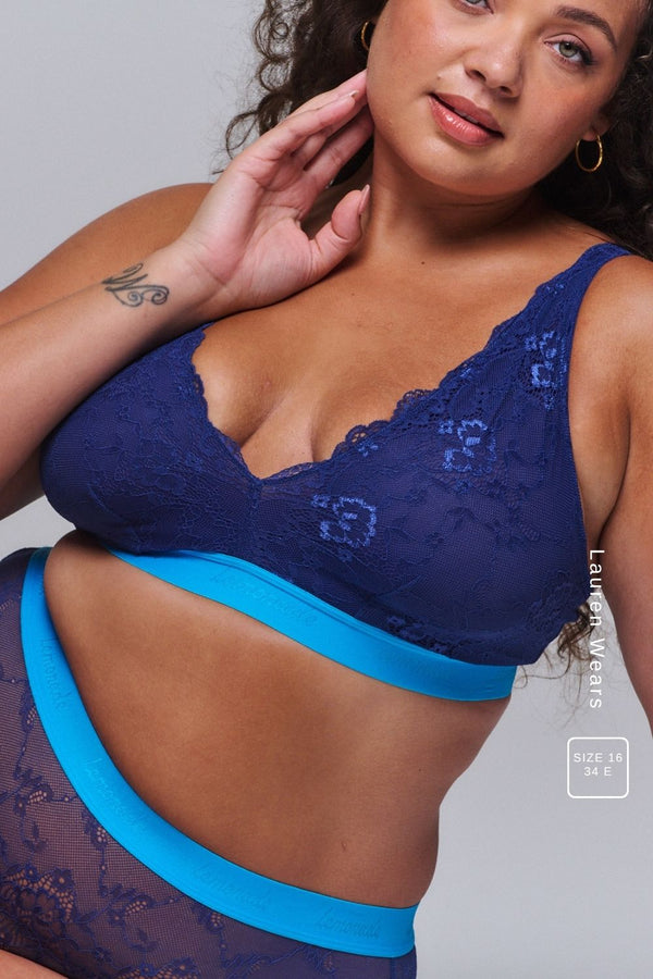 A woman wearing a dark blue lace fuller cup bralette paired with the matching briefs 
