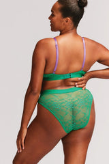 A woman wearing a green lace lingerie set with purple straps 