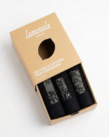 A lemonade dolls box half open, with three pairs of black lace thongs in it 