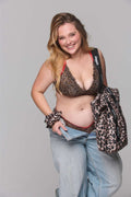 Woman wearing a leopard print top and jeans with a matching bag on a gray background