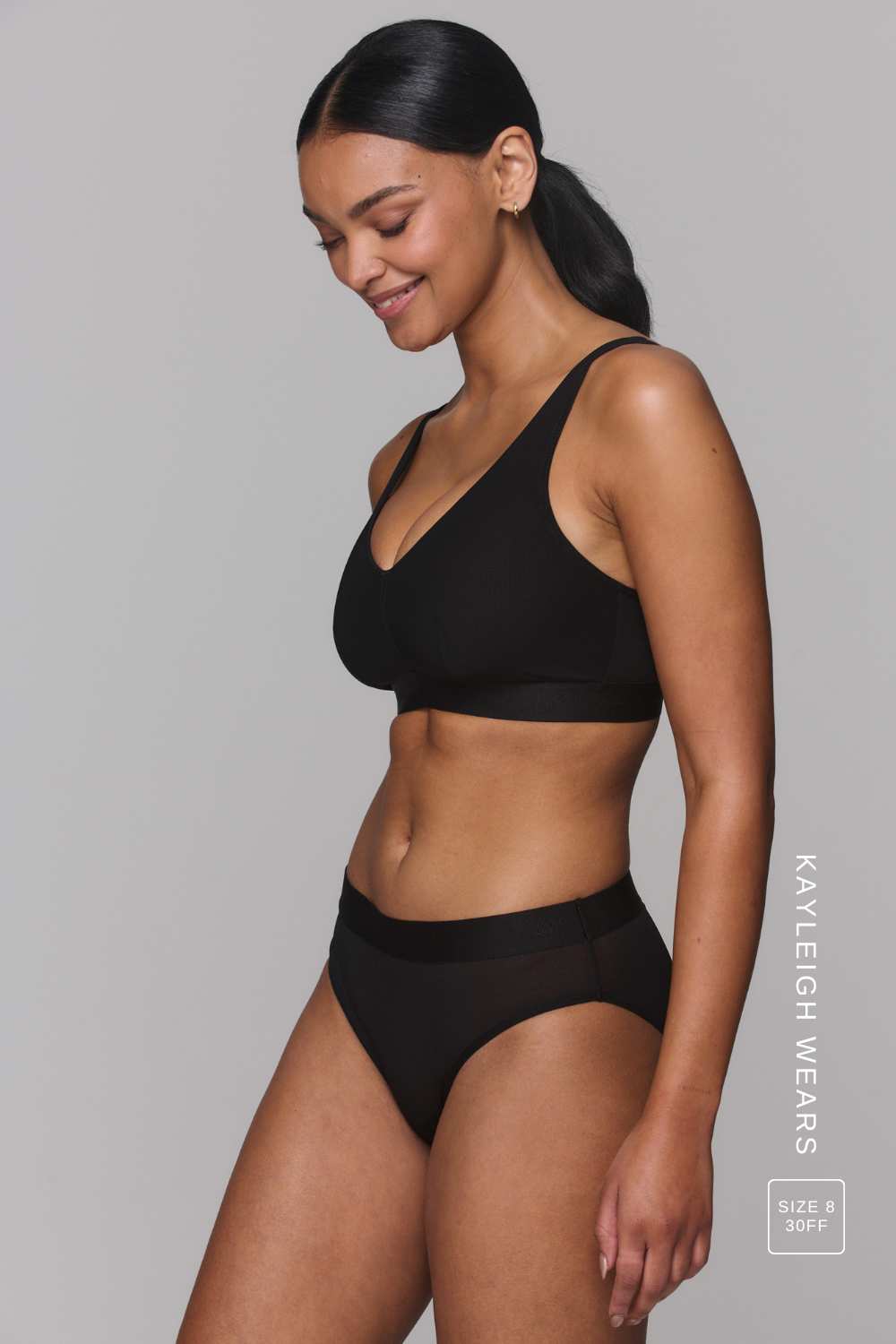 A woman wearing a black mesh fuller cup bralette paired with matching black mesh briefs 