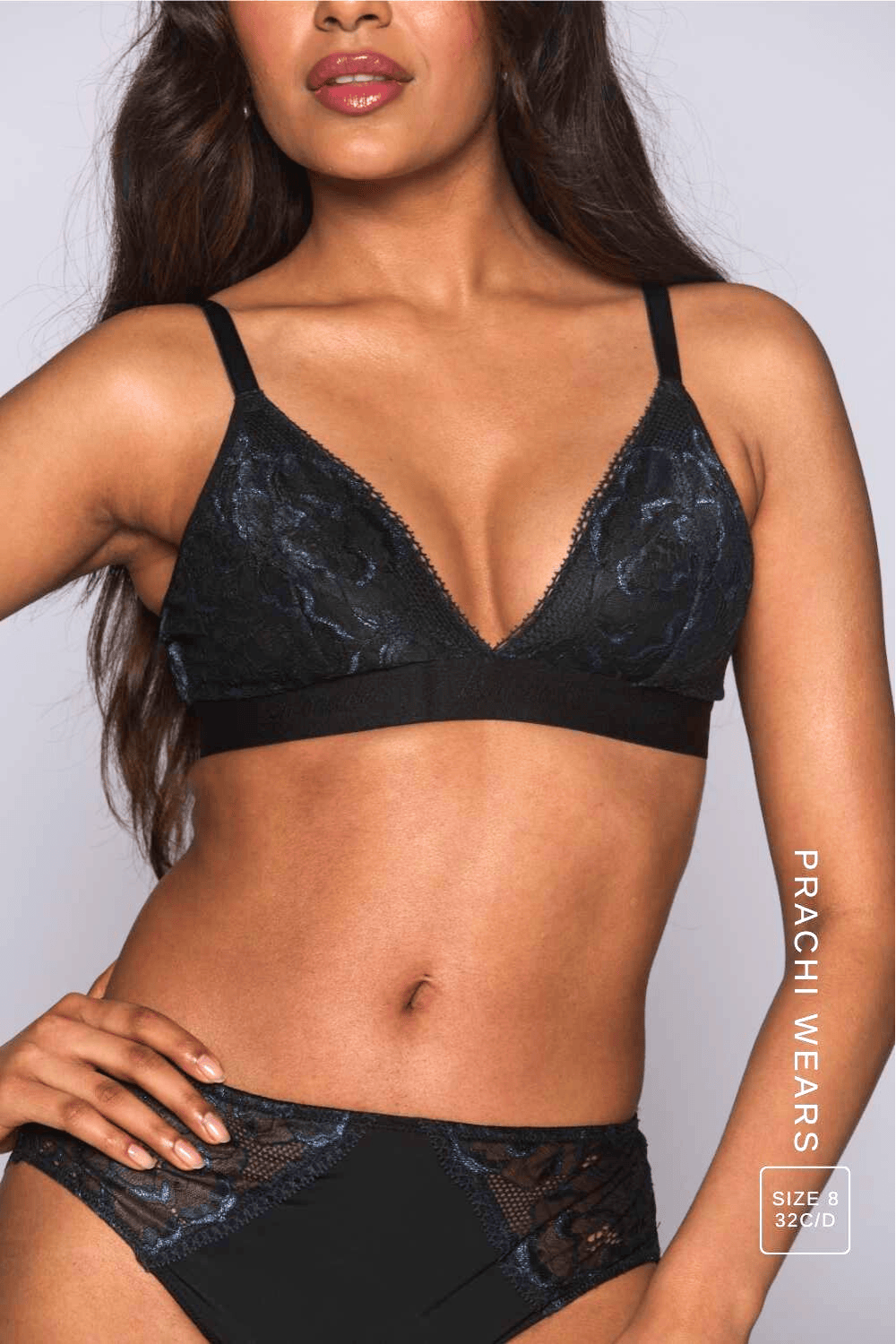 A close up of a woman modelling a black lace bralette called "iridescent" paired with matching briefs