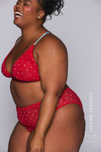 A woman modelling a red mesh bralette with small hearts on it paired with matching briefs 