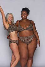 Two woman standing besides each other both wearing a leopard print mesh bralette (one fuller cup) paired with matching leopard print briefs 