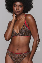 a model wearing a leopard print lace bralette and matching knickers with red edges