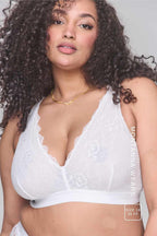 A woman wearing a white lace fuller cup bralette 