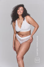 A woman wearing a white V Brazilian paired with the matching white lace bralette 
