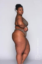 A woman standing with her side to, wearing a leopard print mesh lingerie set 