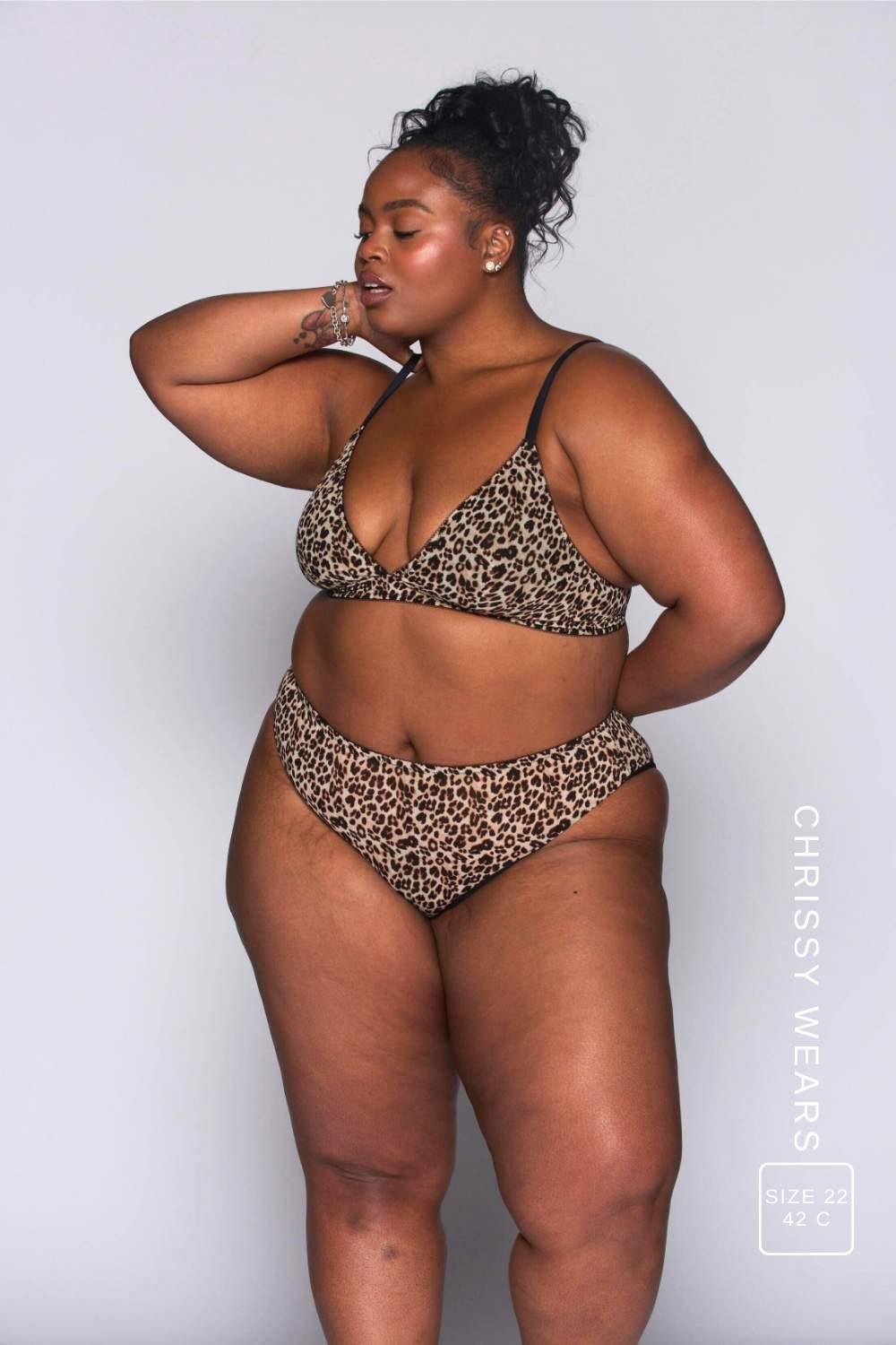A woman wearing a leopard print mesh bralette with black straps paired with matching briefs 