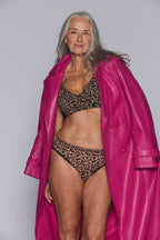 A woman in a pink coat modelling a Leopard Print Mesh Bralette with a matching high waisted brief