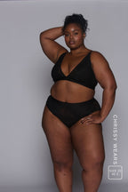 a woman modelling a black lace bralette paired with matching lace knickers 