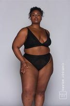 a woman modelling a black lace bralette paired with matching lace knickers 