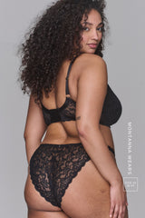 Woman wearing black lace lingerie with branding on a gray background