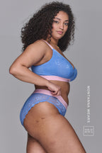 A woman standing with her side to wearing a blue and pink matching lace lingerie set
