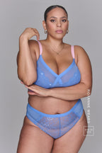 A woman wearing a pink and blue high support lace bra called The One paired with matching knickers 