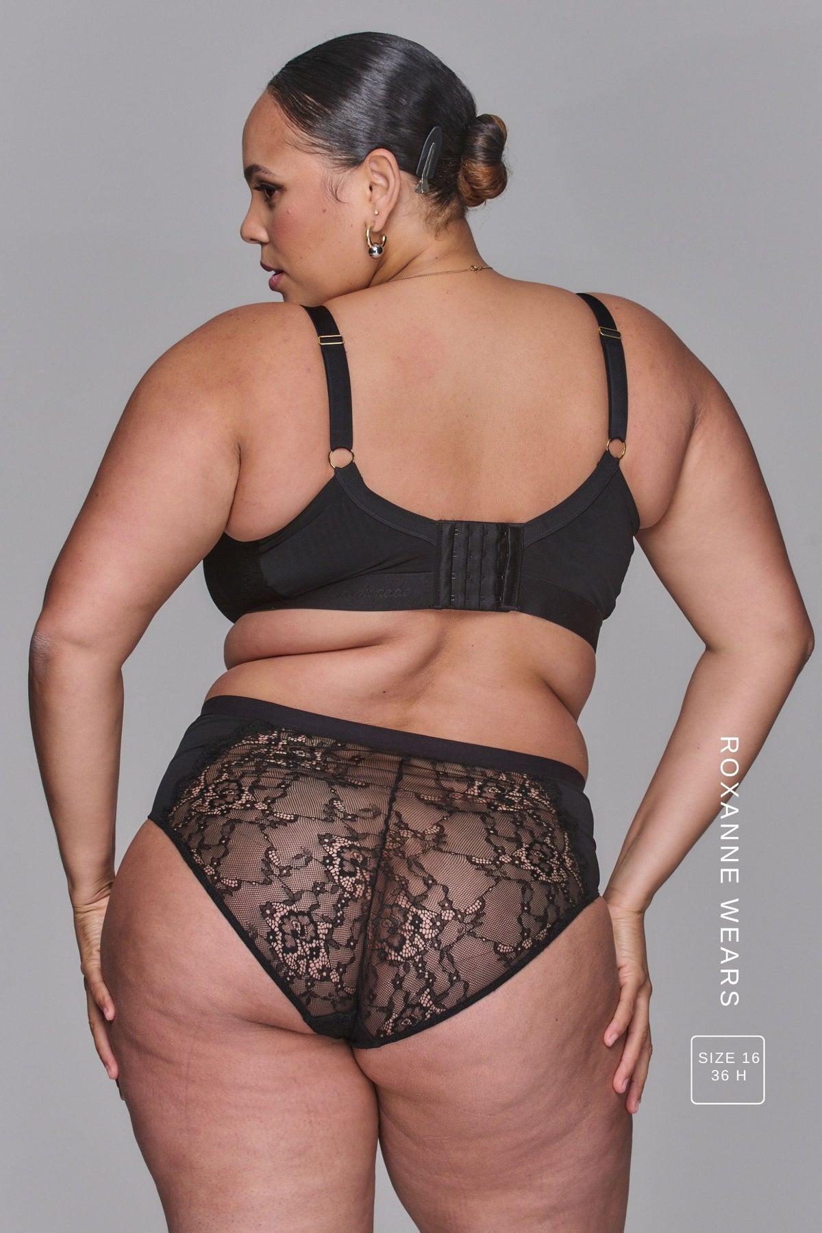 A woman standing with her back turned modelling a Black Lace High Waist Brief paired with a matching black bra
