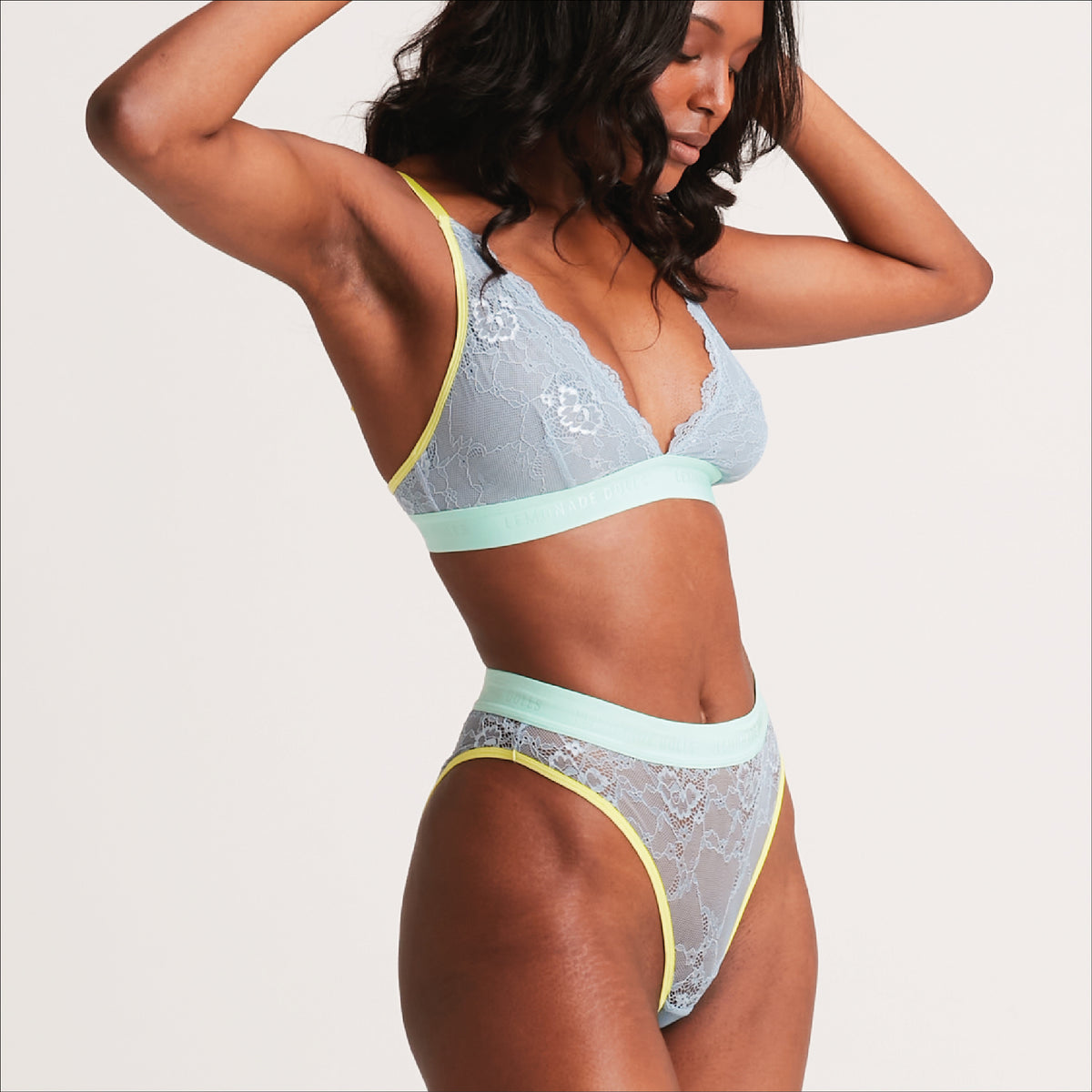 A woman standing with her side to wearing a matching blue lace lingerie set 