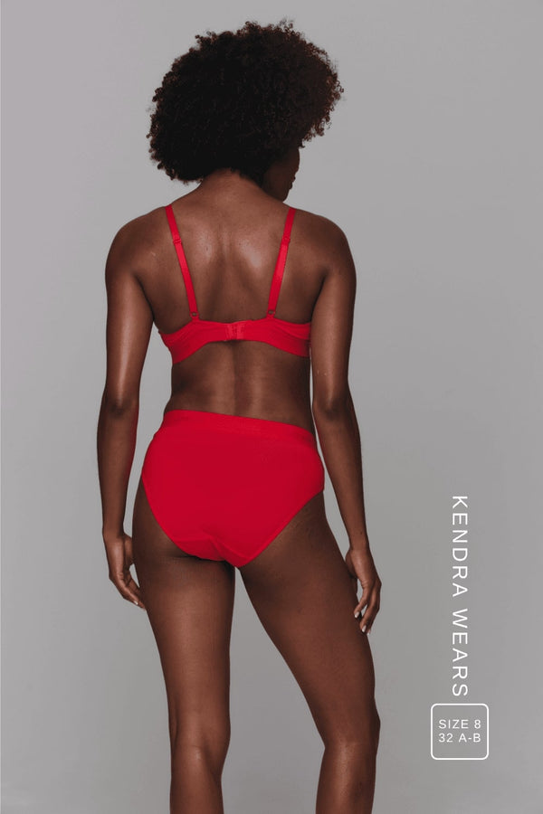 A woman standing with her back to wearing a red modal brief and a matching bralette 