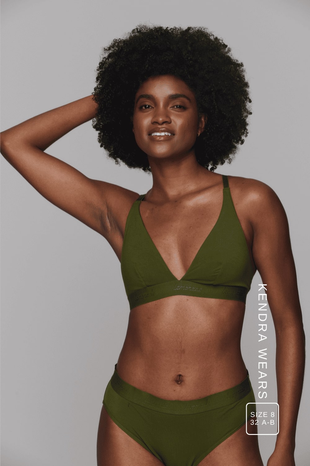 A woman standing with her arm in her hair, wearing a khaki green mesh lingerie set ^Kendra | Size: 32 A-B / 8