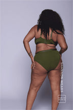 A woman standing with her back to wearing a matching khaki lingerie set 