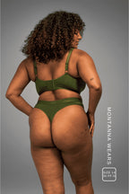 A woman standing with her back to wearing a khaki green thong paired with a matching bralette 