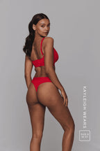 A woman standing with her side to wearing a red mesh lingerie set 