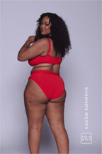 A woman standing with her back to wearing a matching red lingerie set 