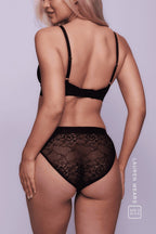 A woman standing with her back to wearing a black lace brief and a matching bralette ^Lauren | Size: 32 B / 8