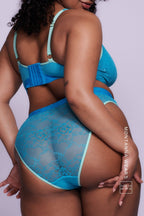 A woman standing with her back to wearing an aqua blue lace brief with light blue details on it 