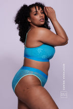 A woman wearing a bright blue lace fuller cup bralette paired with matching briefs