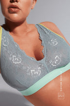 A close up of a woman laying down wearing a blue lace fuller cup bralette 