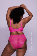 A woman wearing a neon pink lace fuller cup bralette paired with matching briefs 