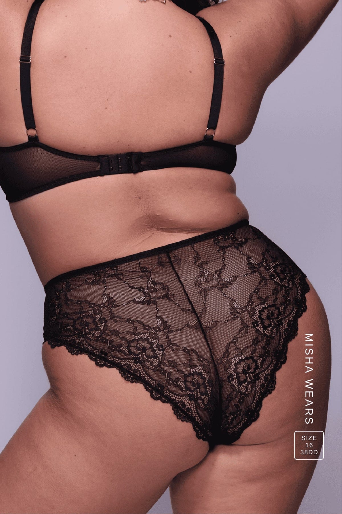 A woman standing with her back turned is modelling a Black Lace Short paired with a Black lace bralette 