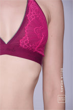 A close up image of the side of a womans chest wearing a pink lace bralette 