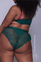 A woman standing with her back to wearing s green and pink lace lingerie set
