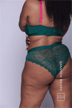 A close up of the back of a woman wearing a dark green lingerie set with pink straps 