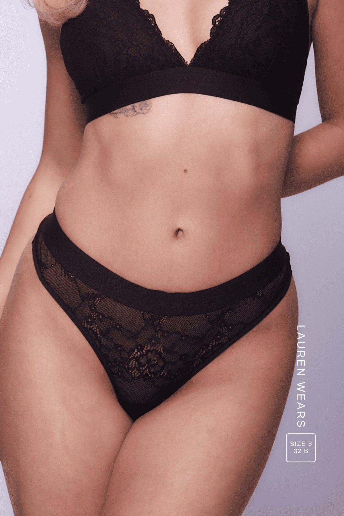A close up image of the front of a woman wearing a black lace lingerie set 