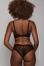 A woman standing with her back to, wearing a black lace lingerie set