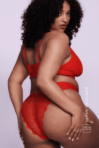 A woman standing with her side to wearing a red lace brazilian knicker 