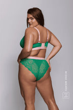 A woman standing with her back to wearing a green lace brief and a matching fuller cup bralette 