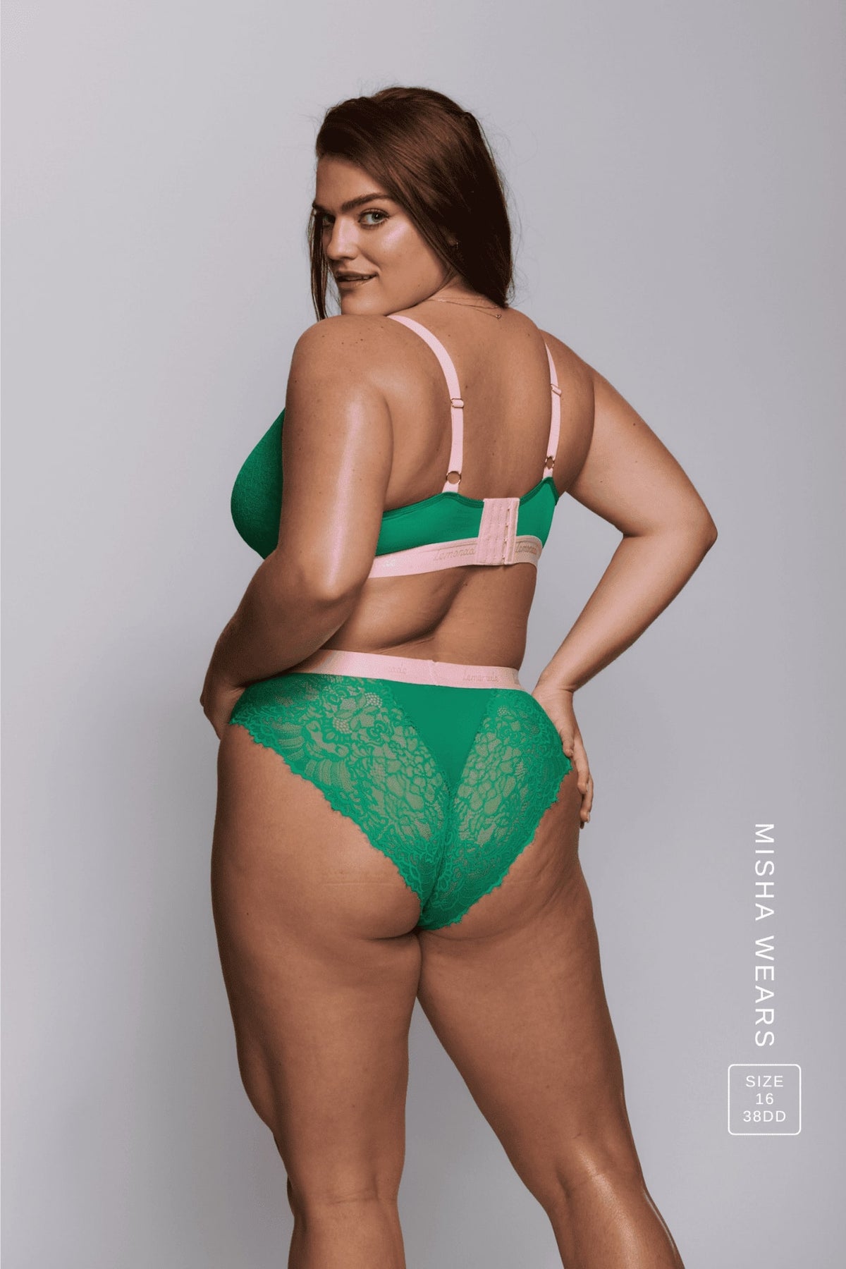 A woman standing with her back to wearing a green lace brief and a matching fuller cup bralette 