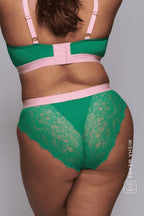 A woman standing with her back to wearing a green lace brief with the matching bralette 