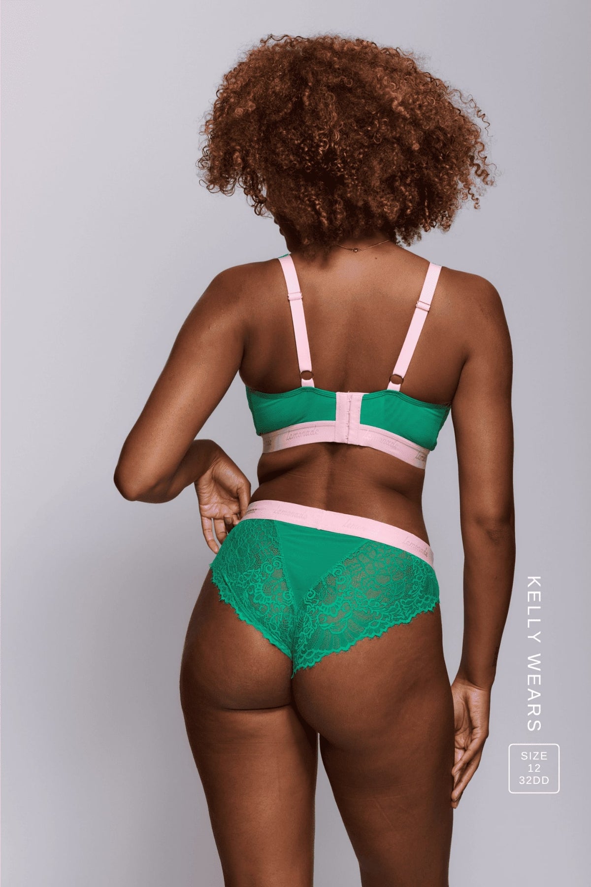 A woman standing with her back to wearing a green lace brief with the matching bralette 