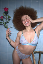 A woman holding two roses in her hand wearing a matching light blue lingerie set ^Yasmin | Size: 32 C-D